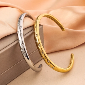 Close-up of star-shaped zircon gold and silver open bracelets on a luxury silk background