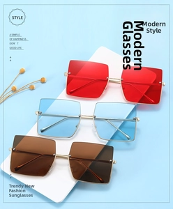 Close-up of retro square sunglasses with red, light blue, and brown lenses in gold metal frames