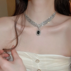 Close-up of vintage silver necklace with black oval gemstone and sparkling zirconias