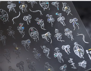 Macro detail of 3D embossed nail stickers featuring white bows and pearl textures