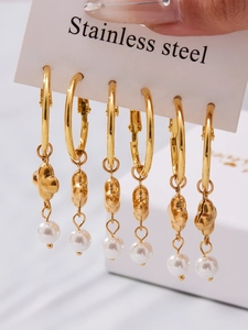 Detailaufnahme von sechs goldenen Edelstahl-Ohrringen mit Perlenanhängern auf Karte