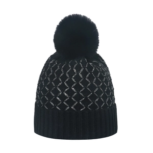 Women's black knit beanie with silver diamond pattern and large faux fur pom-pom
