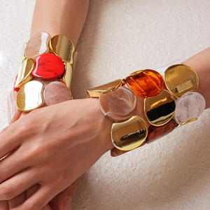 Dettaglio di bracciali elastici in resina con accenti in metallo dorato e acrilico