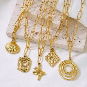 Gold plated stainless steel chunky chain necklaces with varied luxury pendants on marble
