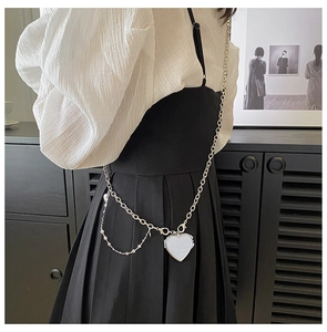 Close-up of silver metal chain strap with heart-shaped pendant on a stylish mini bag