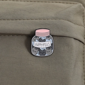 Creative cat enamel pin titled Happy Pills on a beige canvas bag for accessories