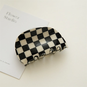 Close-up of a large black and white checkered acetate hair claw clip on a minimal background