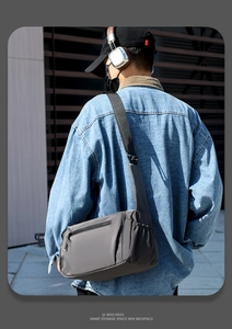Outdoor shot of grey casual crossbody bag with multi-layer zipper storage and durable fabric