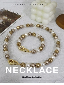 Detail shot of tricolor pearl necklace set with large gold clasp on white fabric