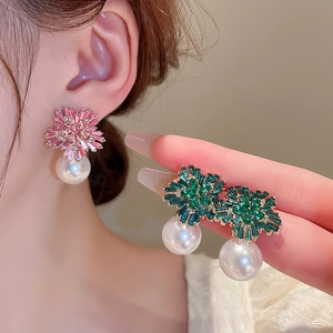 Detailed view of flower-shaped pearl earrings with pink and green zircon petals