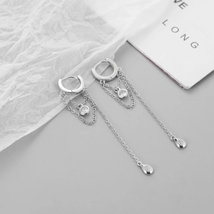 Macro shot of silver chain tassel earrings with zircon studs and star charms