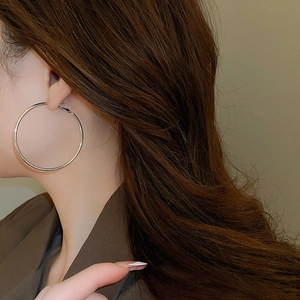 Close-up of model wearing large silver minimalist hoop earrings with a polished metal finish