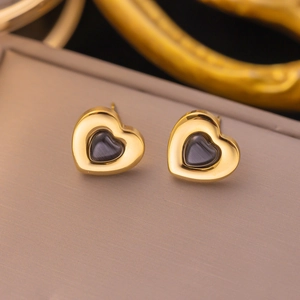 Macro shot of gold-plated heart stud earrings with dark cat-eye stone inlay