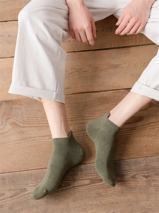 Detail von olivgrünen Kurzsocken mit Fersenlasche auf einem Holzboden