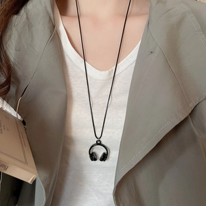 Detail shot of a black headphone pendant necklace on a model with white t-shirt