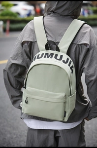 Rear view of a light green large capacity nylon backpack with MUMUJIA print on street