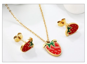 Detail view of gold strawberry pendant necklace and earrings with red enamel