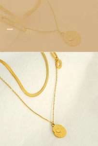 Detail of double-layered gold necklace with flat snake chain and heart coin pendant