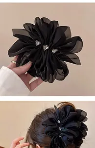 Detail der schwarzen Chiffon-Blumenhaarklammer mit glänzenden Herz-Kristallen