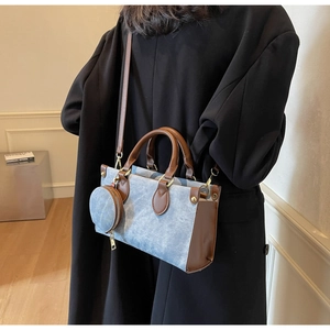 Detail of blue denim canvas and brown leather handbag with mini coin purse on black coat