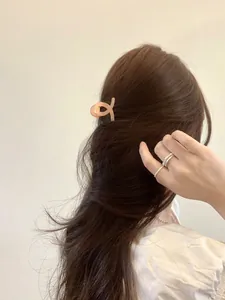 Detail of pink resin hair claw clip and silver ring worn by a model in soft lighting