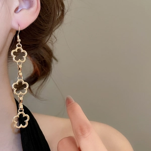 Detail of gold hollow flower tassel earrings on model showing elegant long dangle style