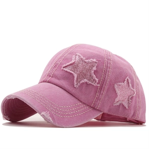 Dettaglio delle toppe a stella glitterate e denim lavato sulla cuffia rosa a coda di cavallo