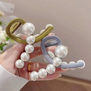 Detail of luxury olive green and grey blue hair claws with elegant white pearl accents
