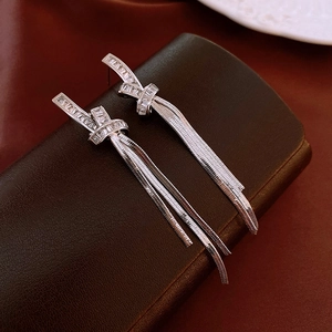 Close-up of sparkling zircon knot earrings with sleek silver tassel fringe details