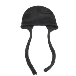Dettaglio del cappello in maglia nera con paraorecchie e lunghi nastri in misto lana
