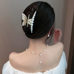 Elegant gold butterfly hair claw clip with rhinestones and pearls shown on model's hair