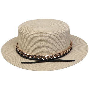 Detailed close-up of straw boater hat with black woven ribbon and gold chain decoration