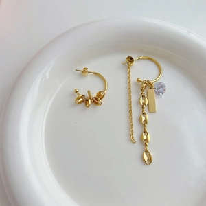Asymmetric gold fringe earrings featuring a balloon dog design on a white ceramic tray