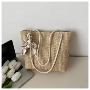 Détail du sac cabas en paille avec poignée en corde et foulard décoratif en soie imprimé