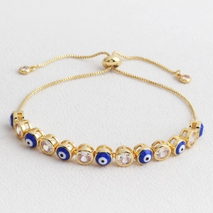 Detail of adjustable gold evil eye bracelet with blue enamel beads and clear zircons