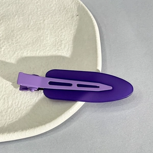 Detail of matte purple seamless hair clips displayed on an aesthetic ceramic plate