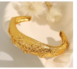 Macro shot of gold flower embossed cuff bracelet with irregular molten lava texture detail
