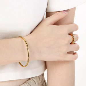 Detail view of model wearing 18k gold plated stainless steel ring and matching bangle set