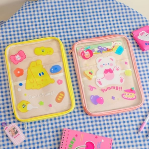 Flat lay of pink and yellow PVC tablet pouches on blue checkered cloth with stationery