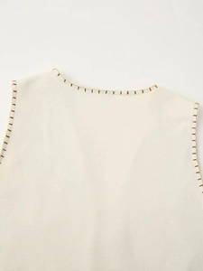 Close-up of cream sleeveless top featuring decorative golden blanket stitch embroidery