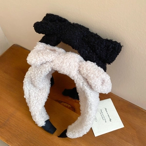 Detail of plush bow headbands in black and beige on a wooden surface for winter