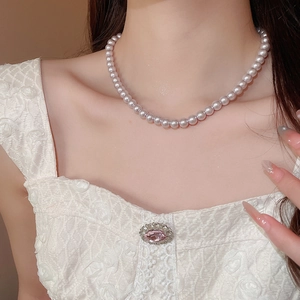 Close-up of pink pearl necklace on model's neck with elegant white lace dress detail