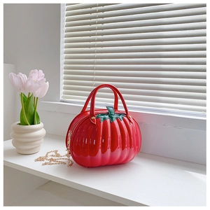Detail of red pumpkin shaped bag with green leaf zipper and gold chain strap