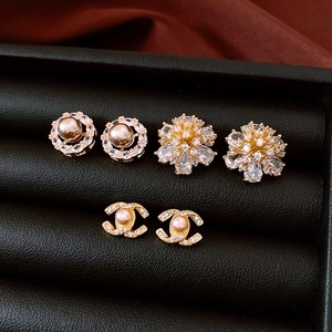 Macro shot of gold-plated flower stud earrings and pearl detail in premium gift box