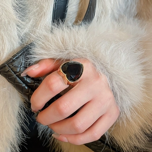 Close-up of heart-shaped black gemstone ring on finger with golden metal setting