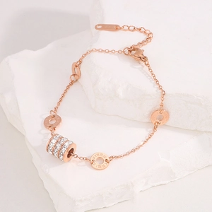 Close-up of rose gold bracelet with roman numeral rings and pave cubic zirconia cylinder