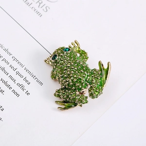 Close-up of a vintage green frog brooch with gold texture and emerald crystal eyes