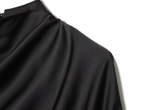 Détail d'un haut en satin noir montrant une texture lisse et des coutures plissées