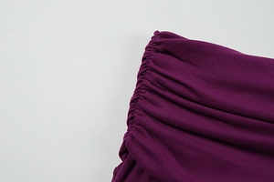Macro detail of the side ruching and pleated texture on this dark purple knitted dress