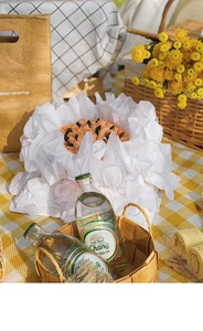 Detail of floral cake wrapped in white crinkled paper on a yellow checkered mat
